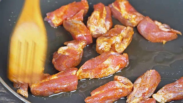 肉片与香料是油炸在一个平底锅近距离观看生的一块肉在煎锅上。视频下载