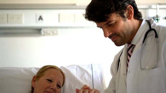 友善的医生叫醒了他的老病人，用平板电脑给她看血检结果视频素材