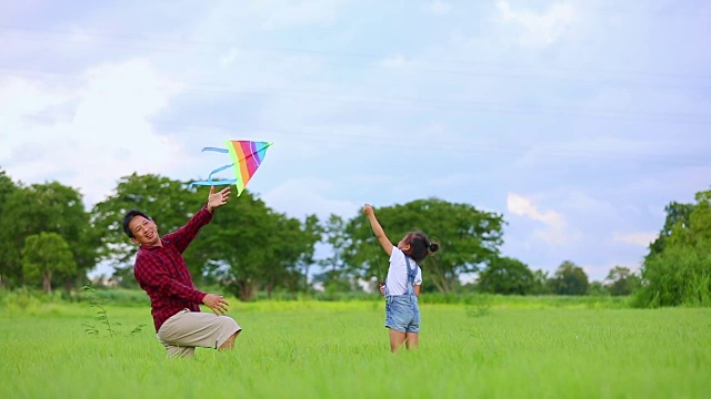 亚洲的小女孩和父亲带着风筝在夏季的草地上奔跑和快乐的大自然中，慢镜头视频素材