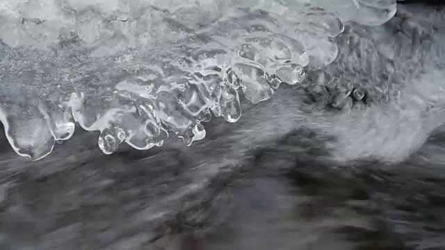 冰冻的山涧。在冰下形成的流动的山溪特写视频下载