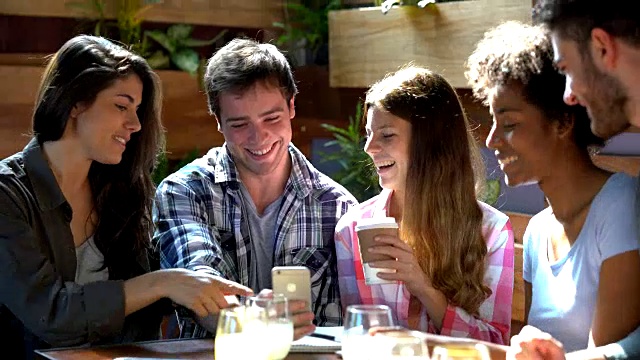 一群朋友在自助餐厅用智能手机浏览社交媒体，时而大笑，时而微笑视频素材