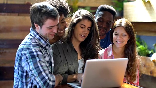 一群快乐的大学朋友学习看着笔记本电脑而美丽的女人解释很友好视频素材