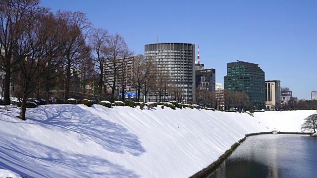 2018年1月23日，日本东京千代田区迎来冬季暴风雪。白雪覆盖的故宫护城河后面矗立着高楼大厦，与护城河的水面交相辉映。视频下载