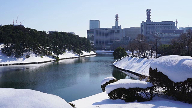 2018年1月23日，日本东京千代田区迎来冬季暴风雪。霞关区和日比谷区的高层建筑耸立在白雪覆盖的故宫护城河后面，这些建筑倒影在护城河的水面上。视频下载