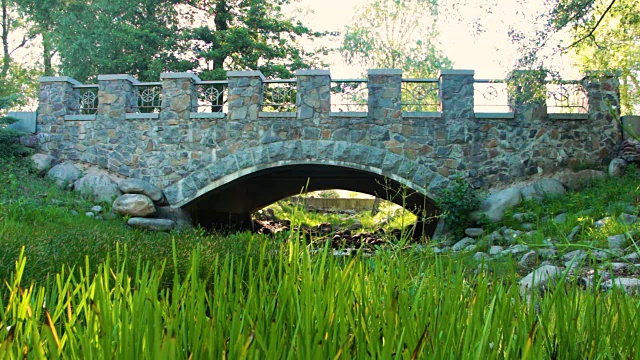 在一个晴朗的夏日，公园里的石桥在一条干涸的小溪上视频下载