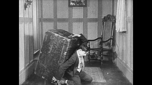 1922年，男人(巴斯特·基顿)举起里面有女人的行李箱视频素材