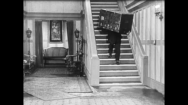 1922年，一个人(巴斯特·基顿)试图把沉重的箱子搬上电气化的楼梯视频素材