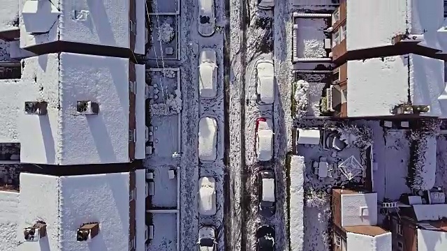 一架飞机在前一晚暴风雪过后被雪覆盖的传统的英国排屋街道上飞行。视频素材