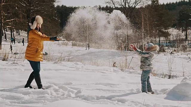 母亲和小女儿玩雪的慢镜头。快乐的冬天休息视频下载