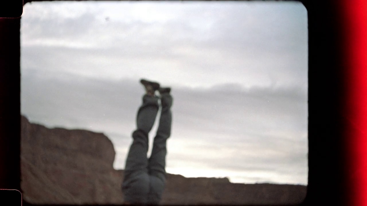 在摩押攀岩之旅中，一名年轻男子在巨石上倒立，并在空中挥舞双手。视频下载