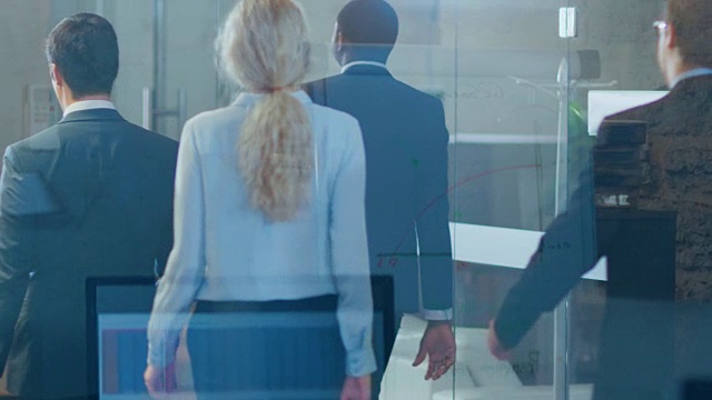坚毅的商人们走过公司大楼走廊的玻璃镜头。视频素材