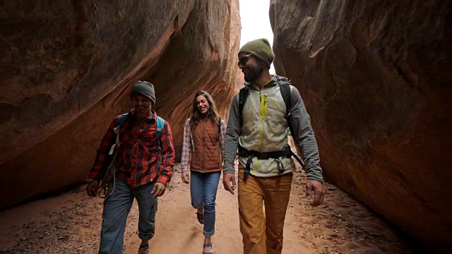 一群朋友微笑着走过砂岩槽峡谷的摩押冒险。视频素材