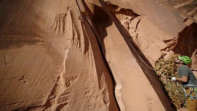 保护者喂绳子，引导攀登者在雄伟的砂岩岩面上高高地攀爬。视频素材