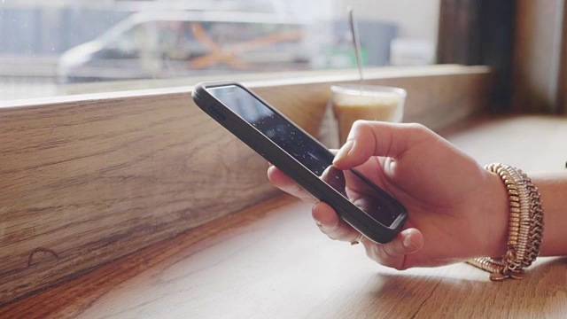 女人的手在咖啡馆使用智能手机的特写视频素材