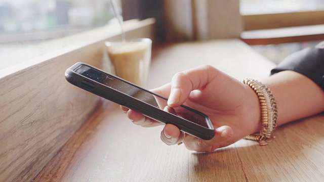 女人的手在咖啡店使用智能手机的特写视频素材