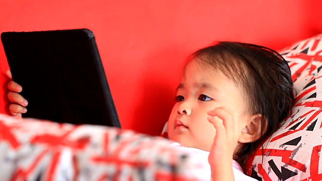WS:小女孩在红色沙发上用平板电脑。视频素材