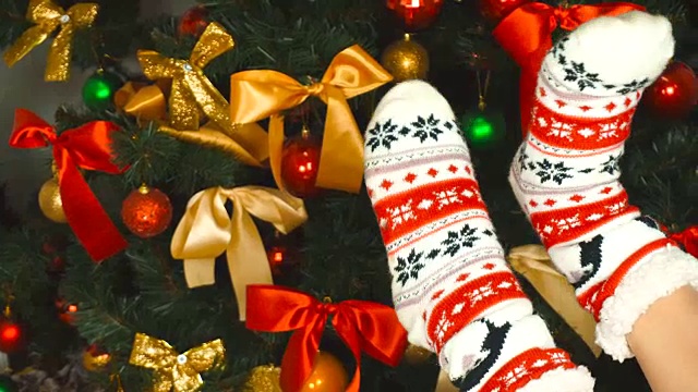 小女孩在圣诞树旁穿着装饰有趣的袜子视频下载