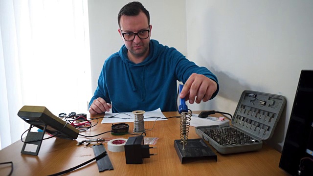 一个年轻人正在焊接电线，在桌子上工作。视频下载