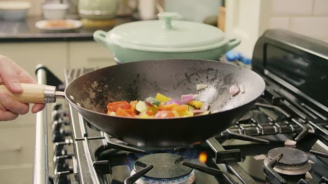 一名男子在厨房炉子上的锅里扔健康蔬菜视频素材