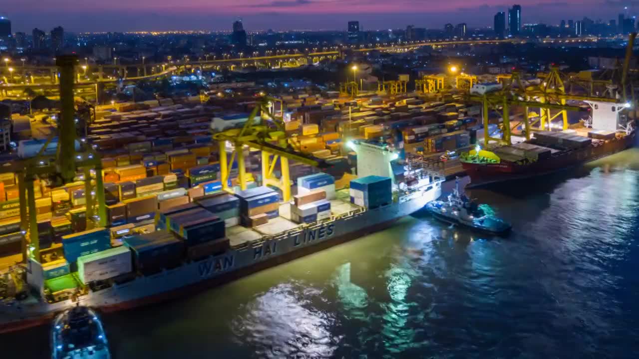 航拍东南亚工业港口与集装箱船在夜间的延时或延时视频素材