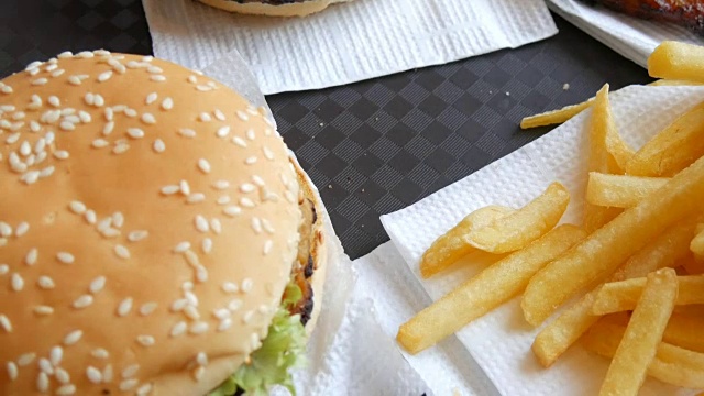 托盘上是快餐。餐桌上的不健康食品汉堡、薯条和炸鸡翅视频素材
