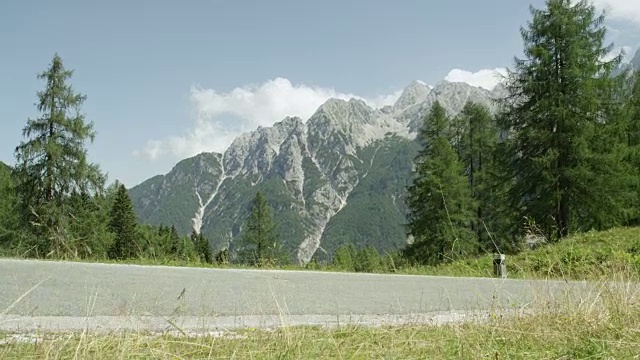 在一个阳光明媚的夏日午后，一名骑山地车的人骑在陡峭的山上。视频素材