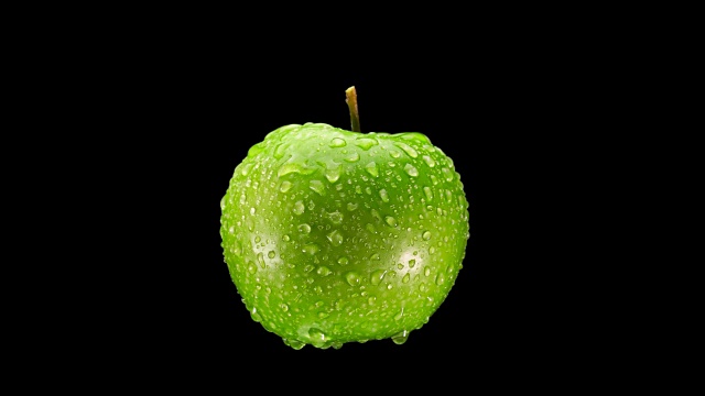 美丽的绿色苹果与水滴旋转的黑色背景，特写视频下载