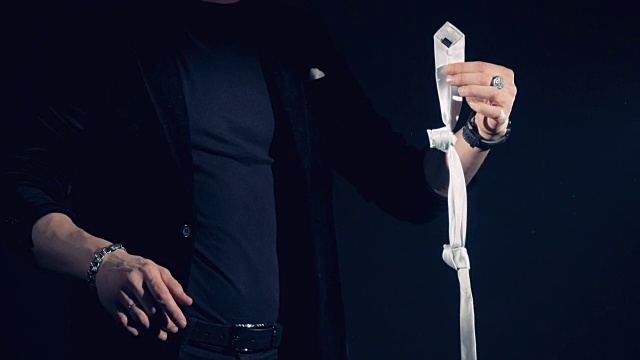 一位魔术师正在表演解开领带上的结的魔术视频下载