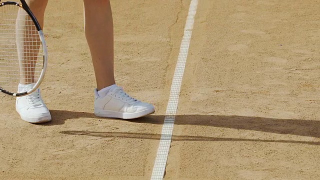 女子发球打网球，穿着舒适的运动鞋进行积极运动，双腿收起来视频下载