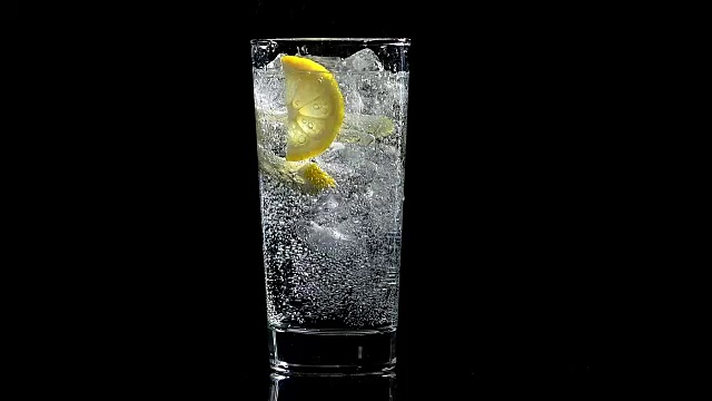 一杯柠檬水和冰块，背景为黑色视频素材