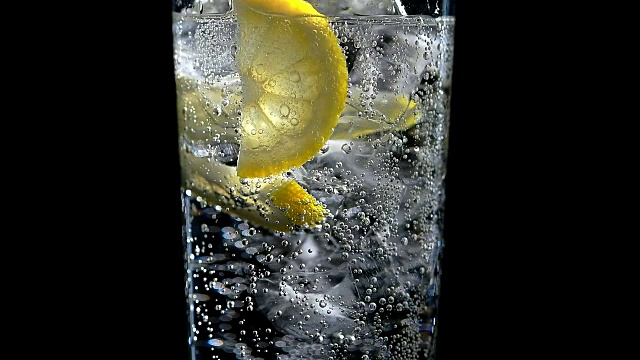 一杯柠檬水和冰块，背景为黑色视频素材