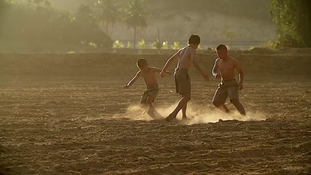 慢镜头，农村的孩子们在阳光明媚的日子里踢足球。视频下载