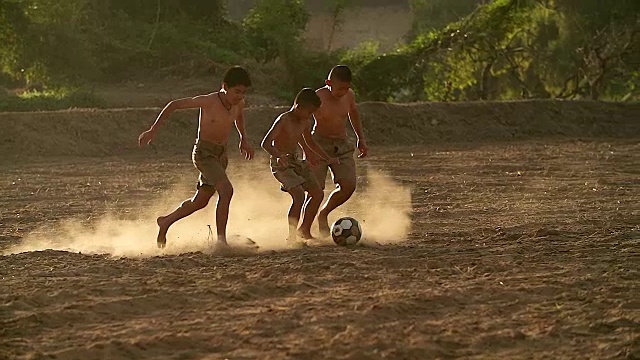 慢镜头，农村的孩子们在阳光明媚的日子里踢足球。视频购买