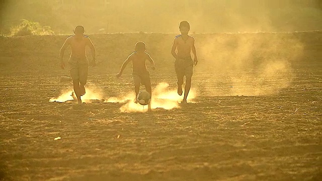 慢镜头，农村的孩子们在阳光明媚的日子里踢足球。视频素材