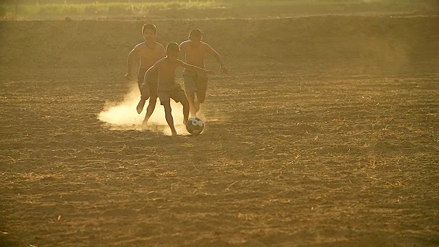 慢镜头，农村的孩子们在阳光明媚的日子里踢足球。视频素材