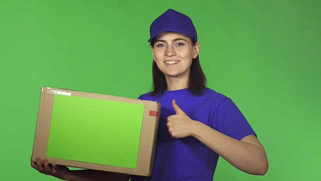 有魅力的年轻送货女举起大拇指举着纸板箱视频下载