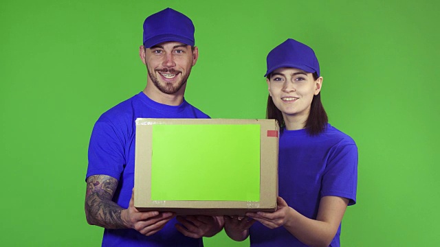 两名快乐的专业快递员对着镜头举着包装盒视频下载