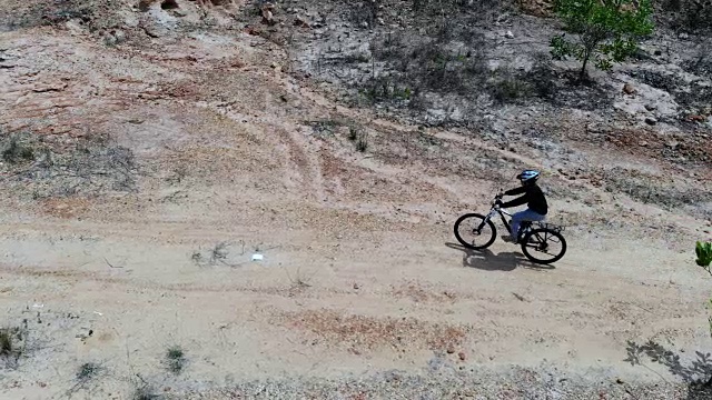 女子骑山地车在山公园，无人机拍摄俯视图视频下载