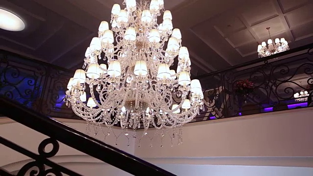 豪华的大型水晶吊灯悬挂在宫殿里。带有灯泡和许多吊坠的老式照明灯具。古代大厅的富丽堂皇。视频素材
