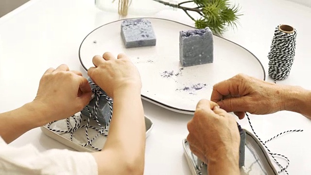女人的手与她的母亲，同时制作工艺肥皂的礼物，他们在他们的小房间工作手工和自制产品的小商业概念视频素材
