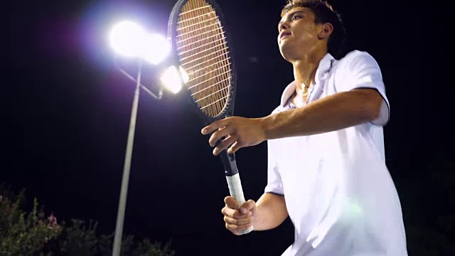 流汗的男子网球运动员在晚上在室外场地练习网视频下载