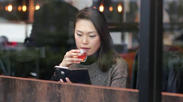 饮用绿茶和使用智能手机的日本妇女。日本东京视频下载