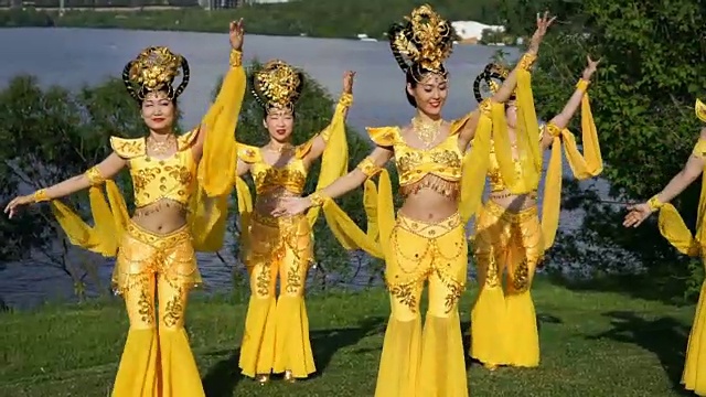 五名亚洲女演员穿着中国传统的黄色服装在河边跳着美丽的舞蹈视频素材