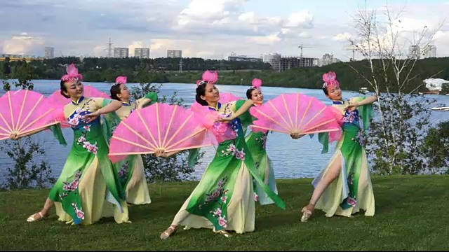 五名亚洲女演员身着中国传统服饰，与粉丝们在河边户外跳舞视频素材