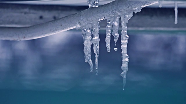 融化的冰柱和水滴靠近。冬天结束了，室外的水从冰柱上滴下来视频下载