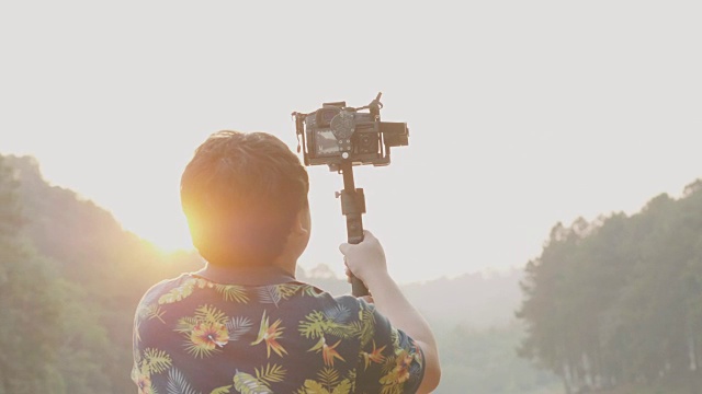 电影制作人的背后，他一边工作一边用阳光效果拍摄大自然的电影录像——在户外工作视频下载