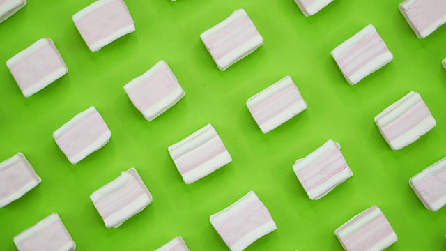 明亮多彩的棉花糖特写微距拍摄在一个绿色的背景。旋转的俯视图视频下载