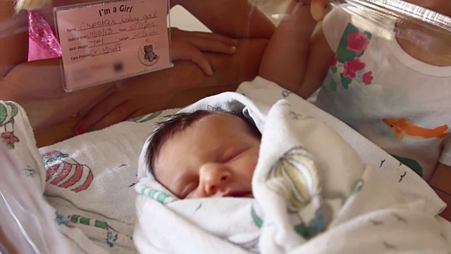 两个小女孩在医院的婴儿床上看着刚出生的婴儿视频下载