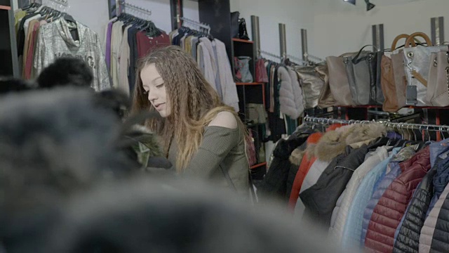 时尚的女顾客在商场里为她的秋冬衣柜挑选基本的衣服视频下载