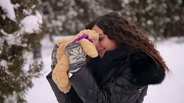 怀孕的女孩在冬天的公园里带着一只泰迪熊。视频素材